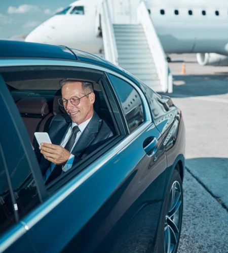 A businessman sitting in a luxury black limo at airport with a private jet in the background