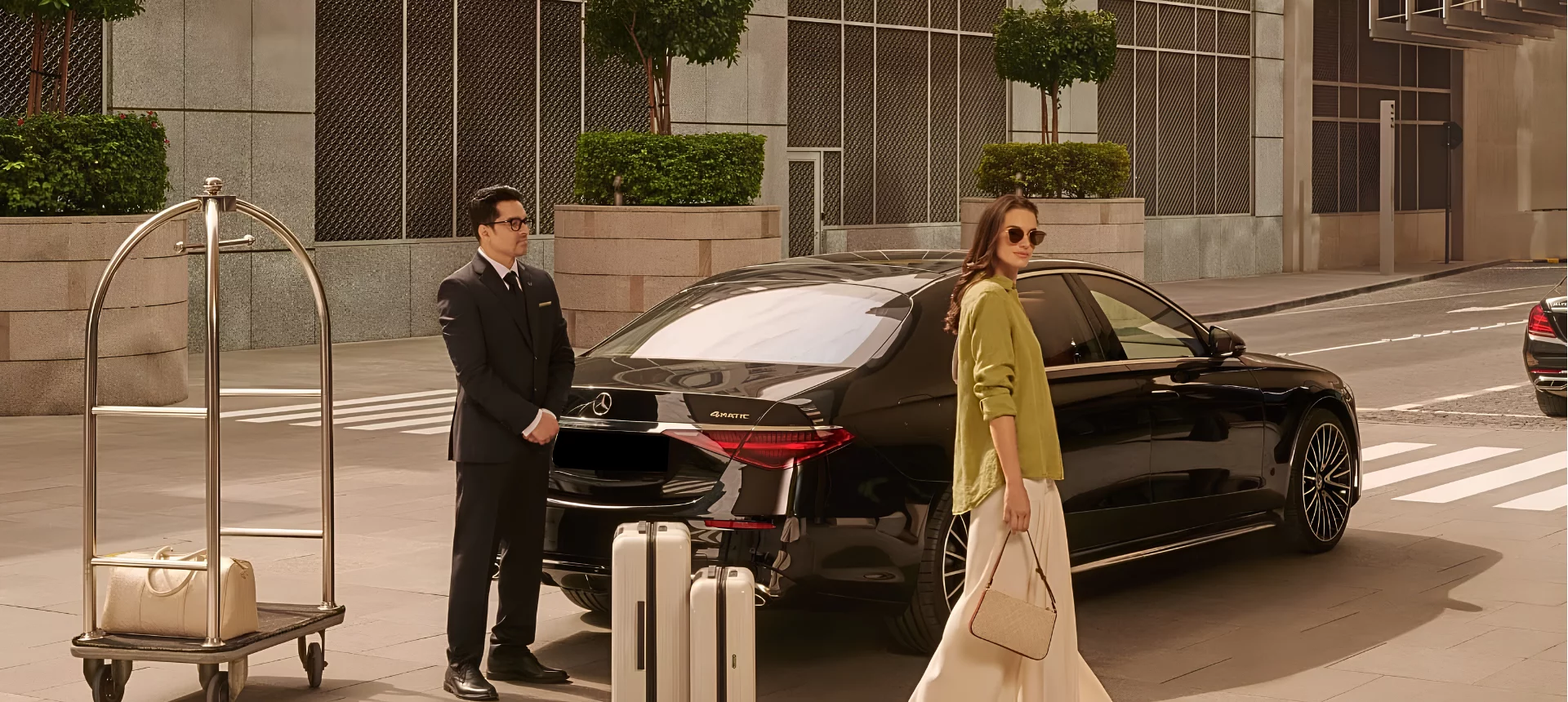 A professional chauffeur assisting a passenger with her luggage at the enterance of a hotel