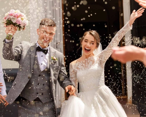 A beautifull couple celebrating their wedding while the groom is holding a flower bouquet