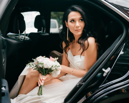 bride sitting in limo holding flower bouquet