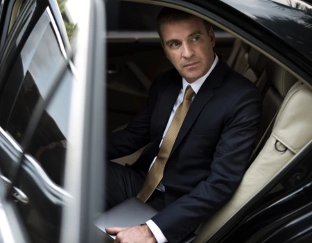 A businessman sitting in a limo and going to a corporate event