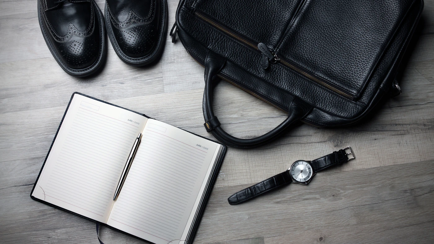 Open notebook, watch and work bag arranged for business trip planning