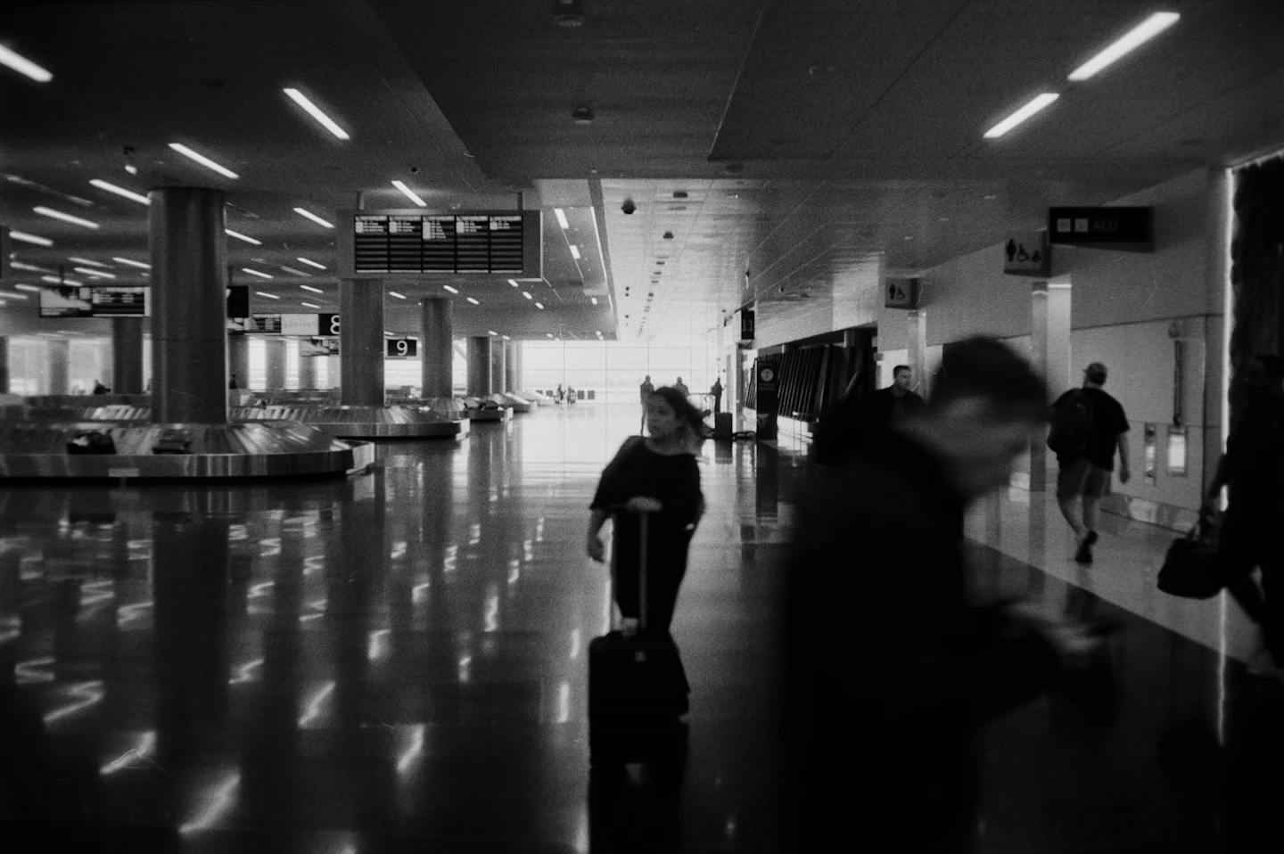 Travelers walking through an airport terminal with rolling luggage; stock photo