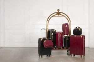 Red and black suitcases arranged on and around a hotel luggage cart
