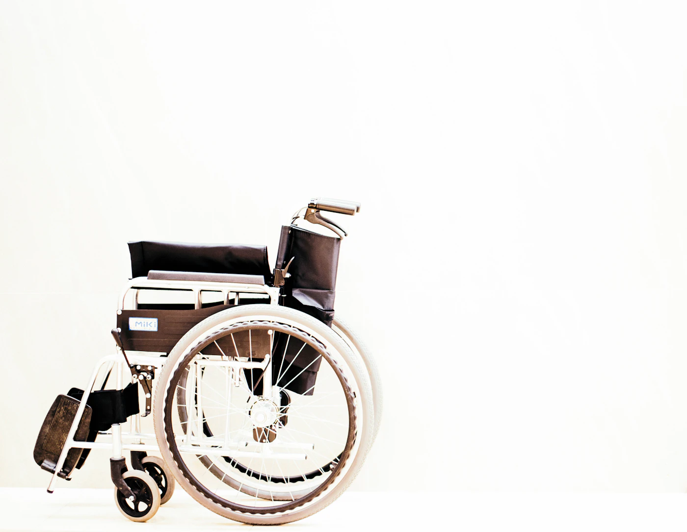 Manual wheelchair with black seat and silver frame against a white background
