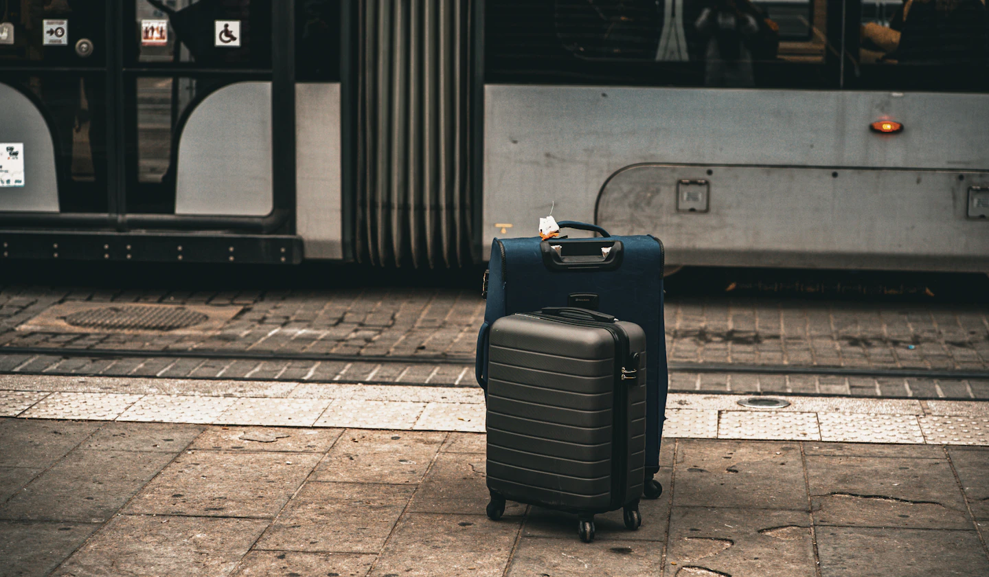 Two suitcases beside public transport; stock travel-planning photo